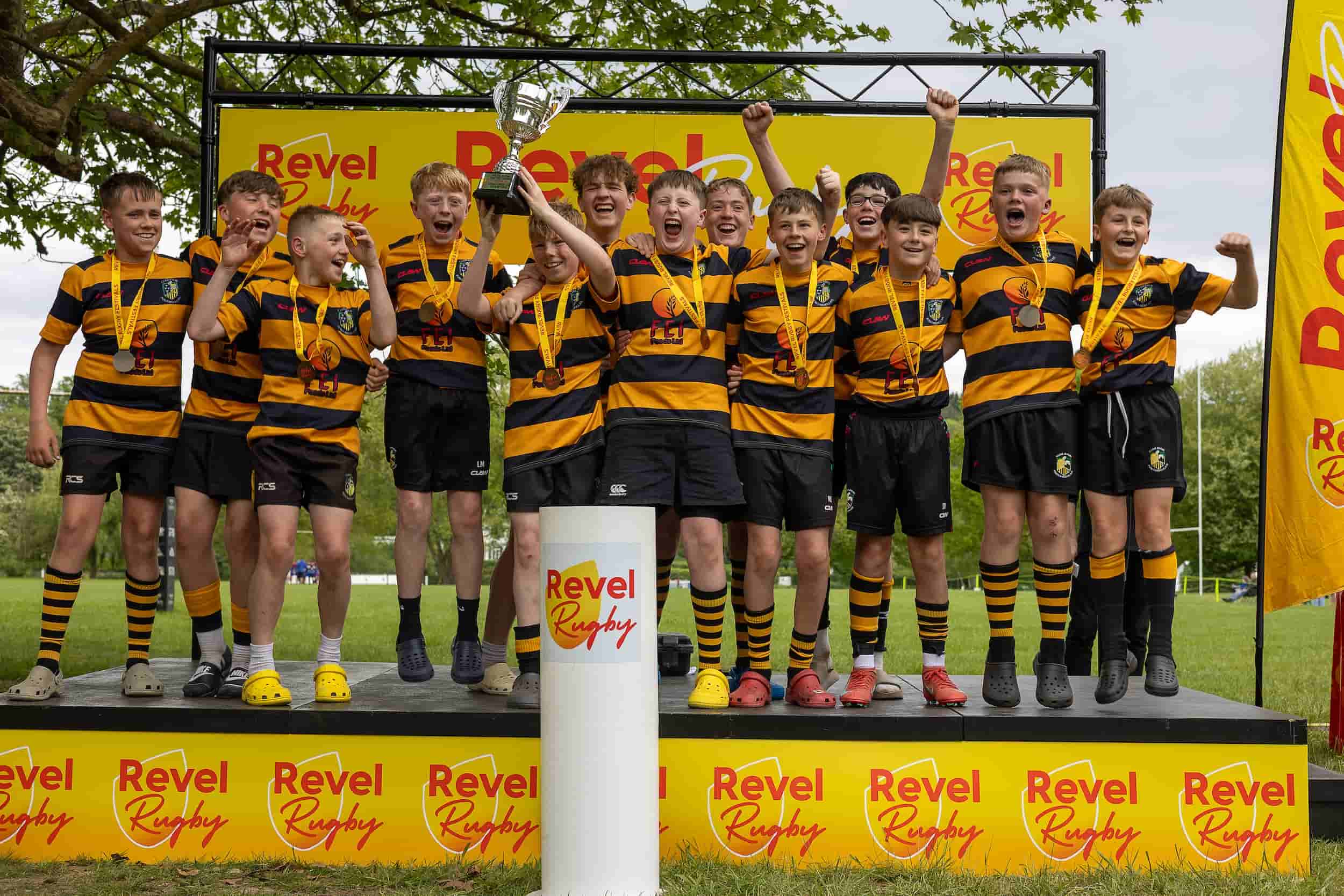 Squad celebrating with the cup on the Revel Rugby podium